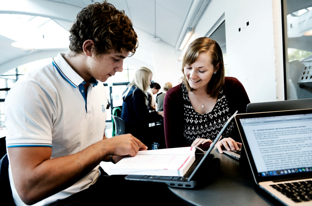 Two students talking over a book 