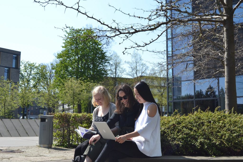 Students sitting in front of the Solbjerg Plads campus and looking at a computer